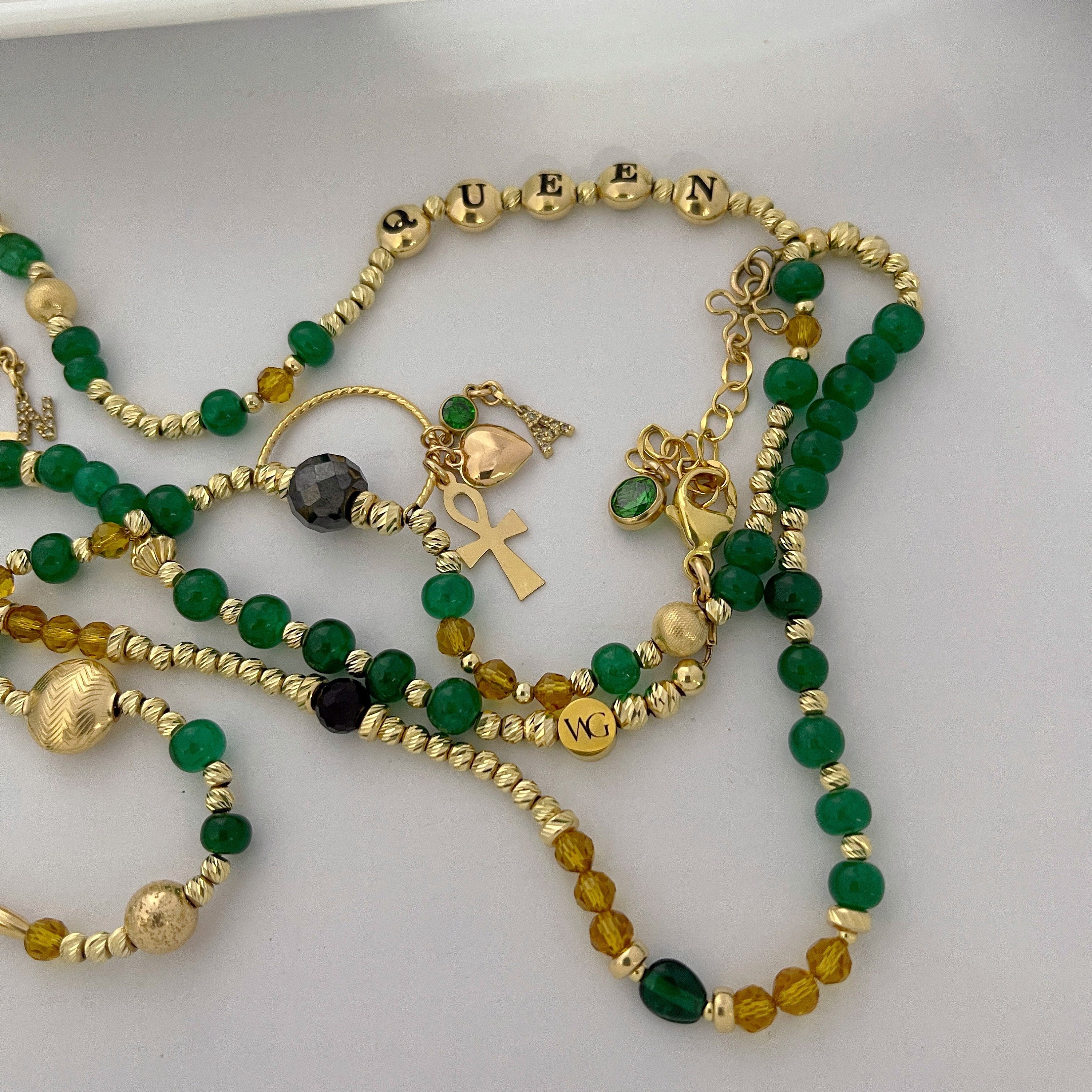 Black Diamond, Beryl Emerald, and Citrin 14k solid gold faceted beads strung onto a 14k gold chain closed with a lobster claw clasp. The word Queen is spelled out with domed flat round beads with letters. Also attached are 2 diamond initial charms N & A along with 2 hearts and 2 Ankh Charms connected to a gold charm holder..