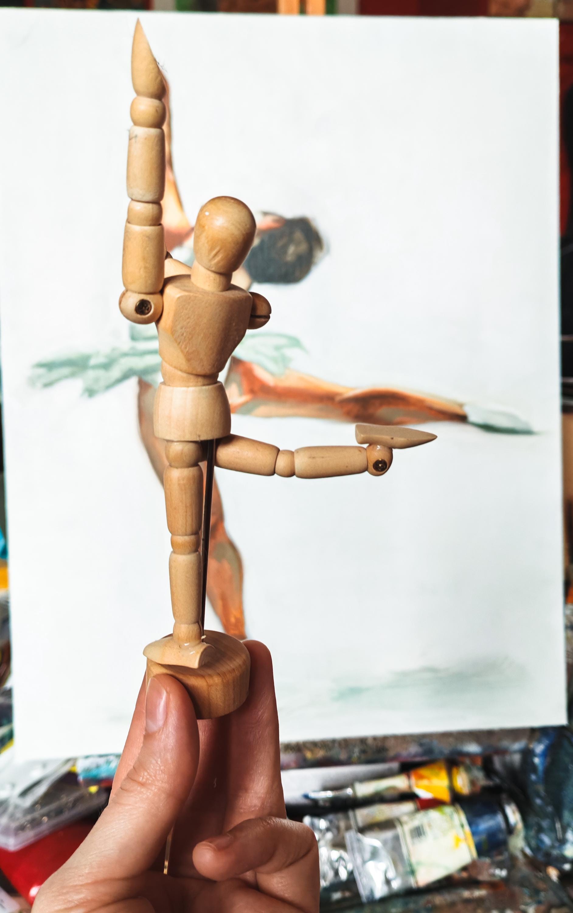 An oil painting of a figure skating spin obscured by a small wooden art mannequin held up by a hand. The mannequin is mimicking the pose of the figure in the painting.