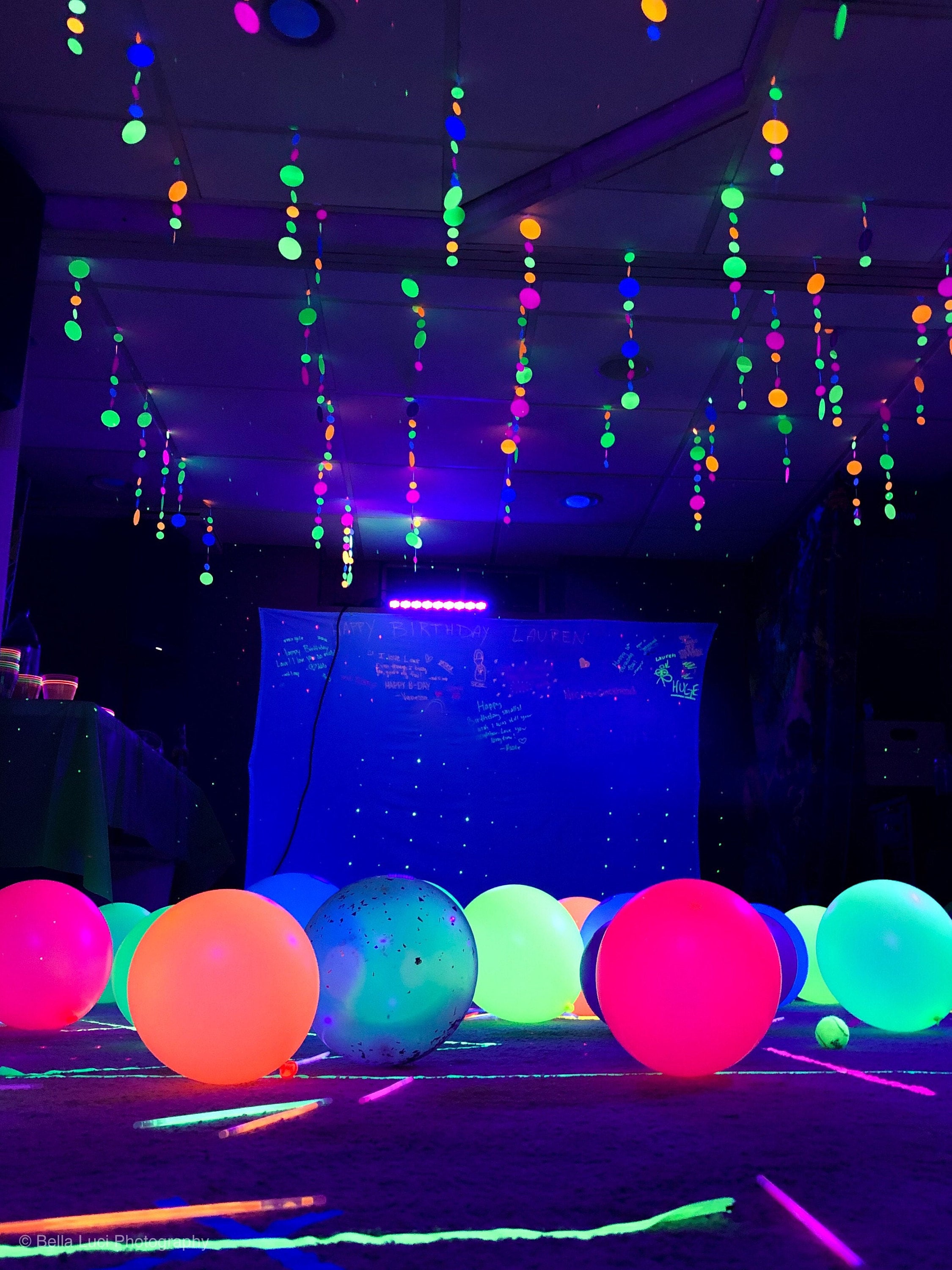 glowing balloons on dance floor at glow party with glowing garlands hanging from ceiling