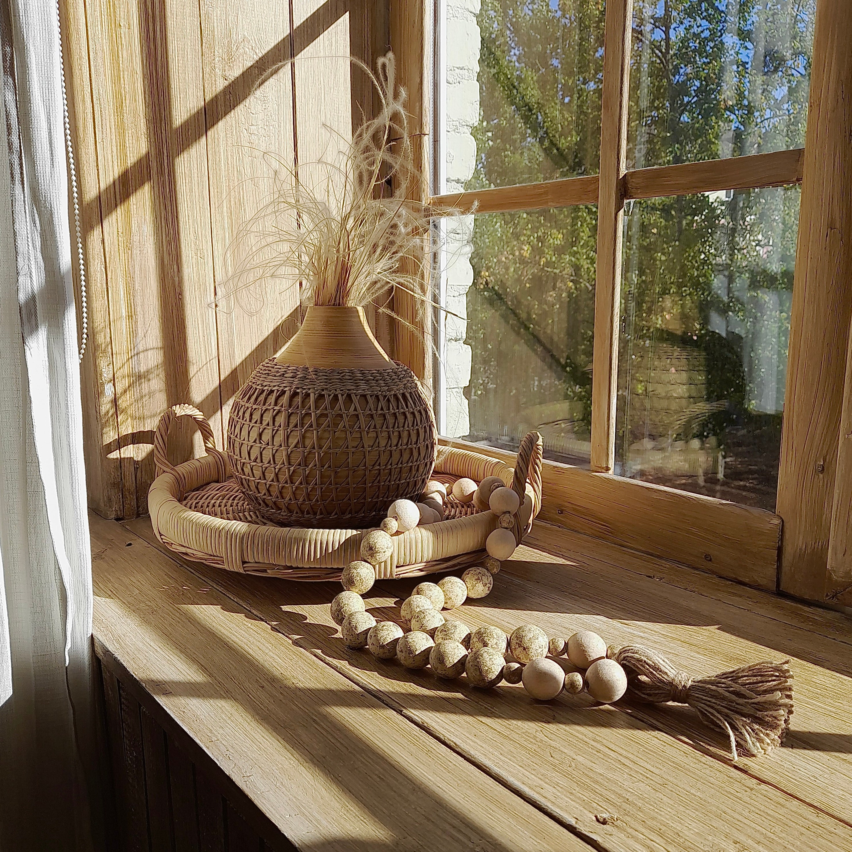 Wicker vase, wicker tray, wood beads garland on the windowsill