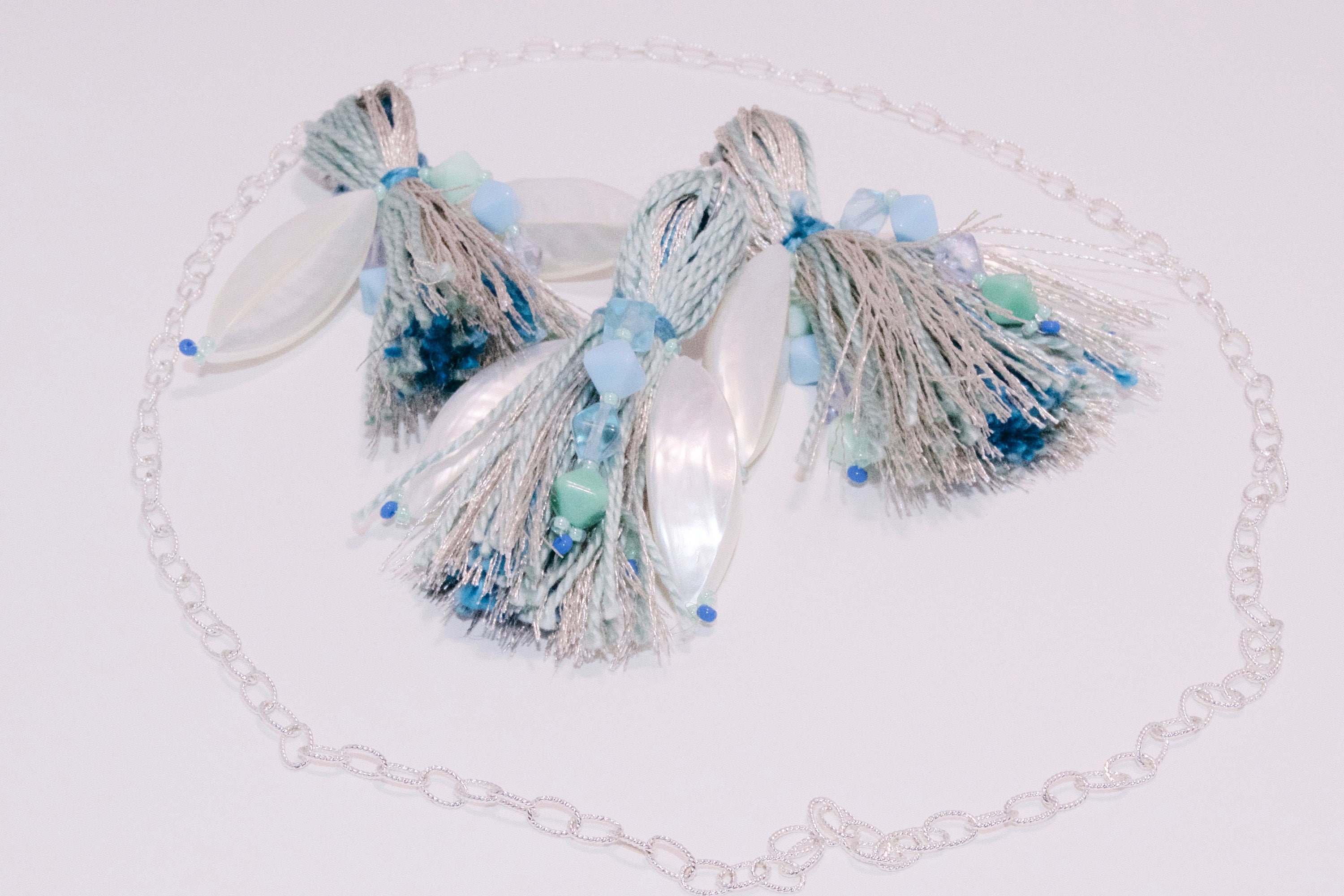 Three tassels in silver and sea green with a large pearlescent bead each and a silver chain around them