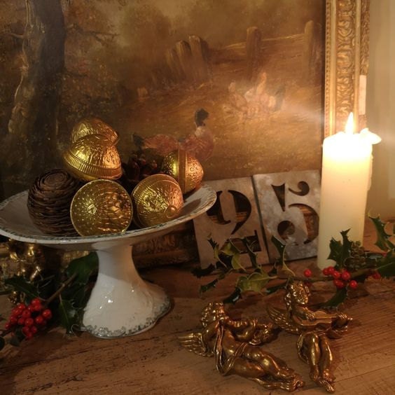 An antique French ironstone compote loaded with baubles and fir cones flickering in the candlelight