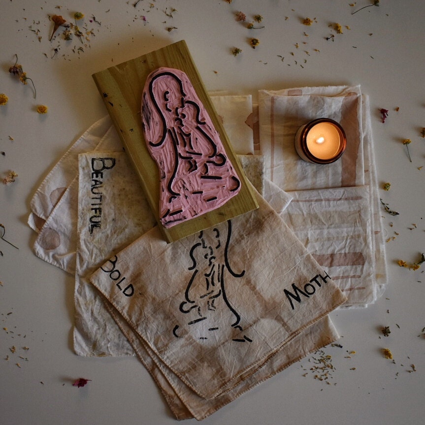 custom stamp of mother and child on a table with a candle and stamped bandanas