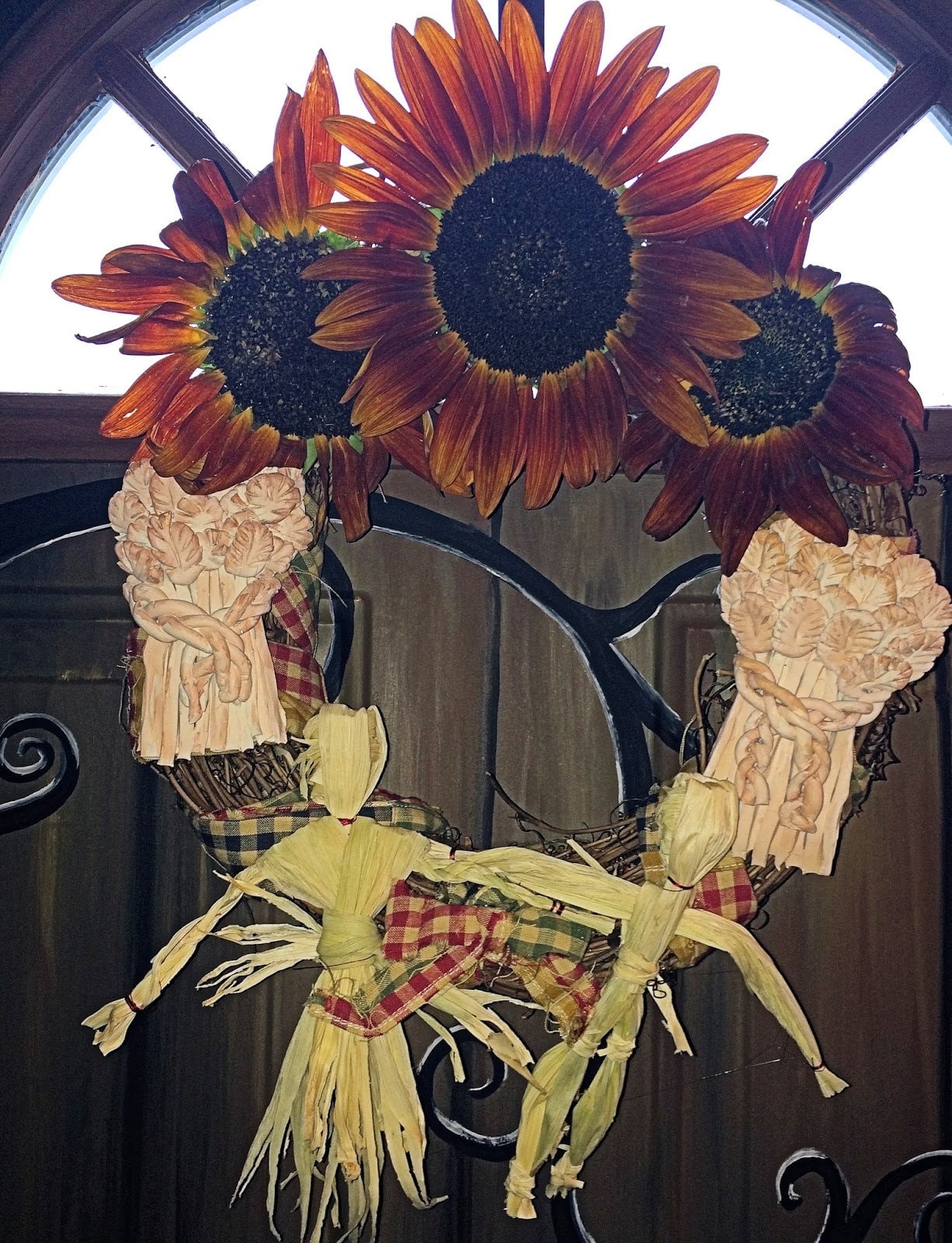 Lughnasadh wreath assembled with sunflowers, corn dollies, and clay wheat