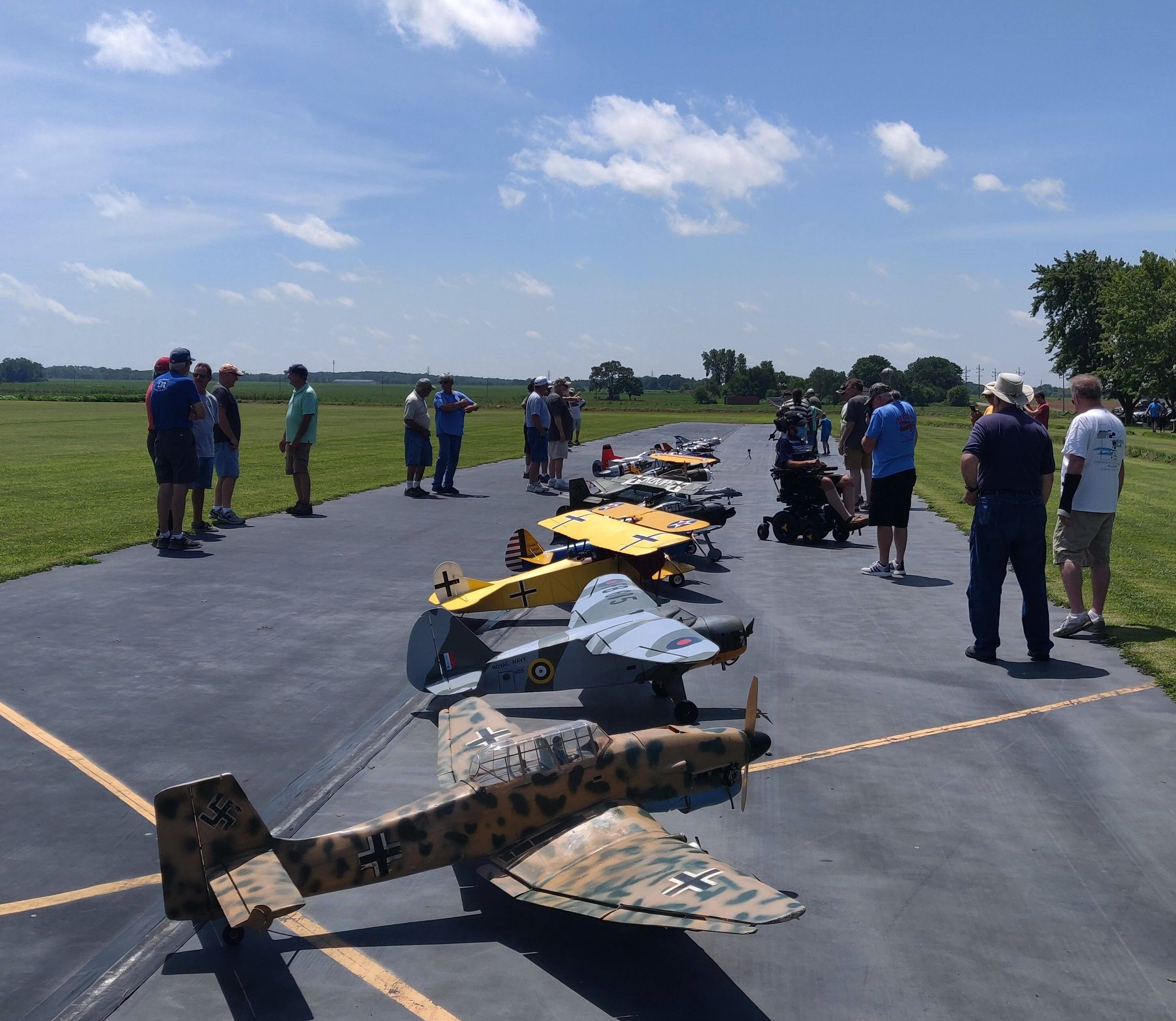 RC plane event with several RC planes being showcased in ARC Club landing strip with individuals Interacting with one another
