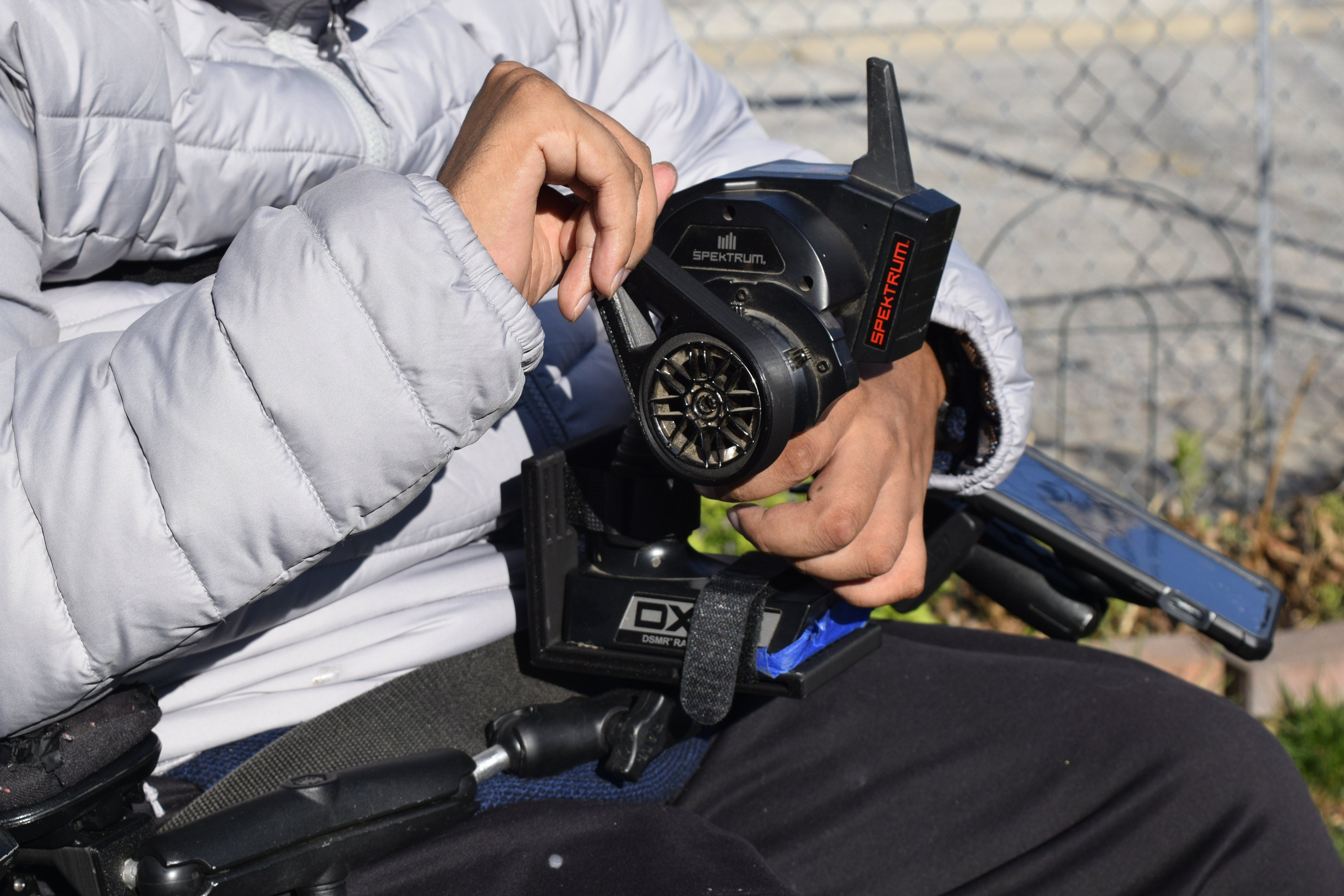 RC car remote controller mounted onto a permobil electric wheelchair with a universal transmitter mount provided by accessiblehobbies.com