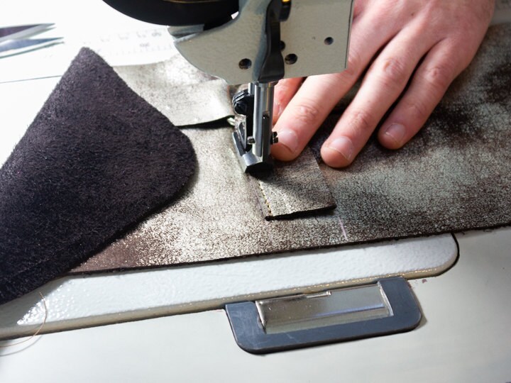 Close up of Mad Hatter Warped & Woven artisan sewing together a handbag made with copper foil leather.