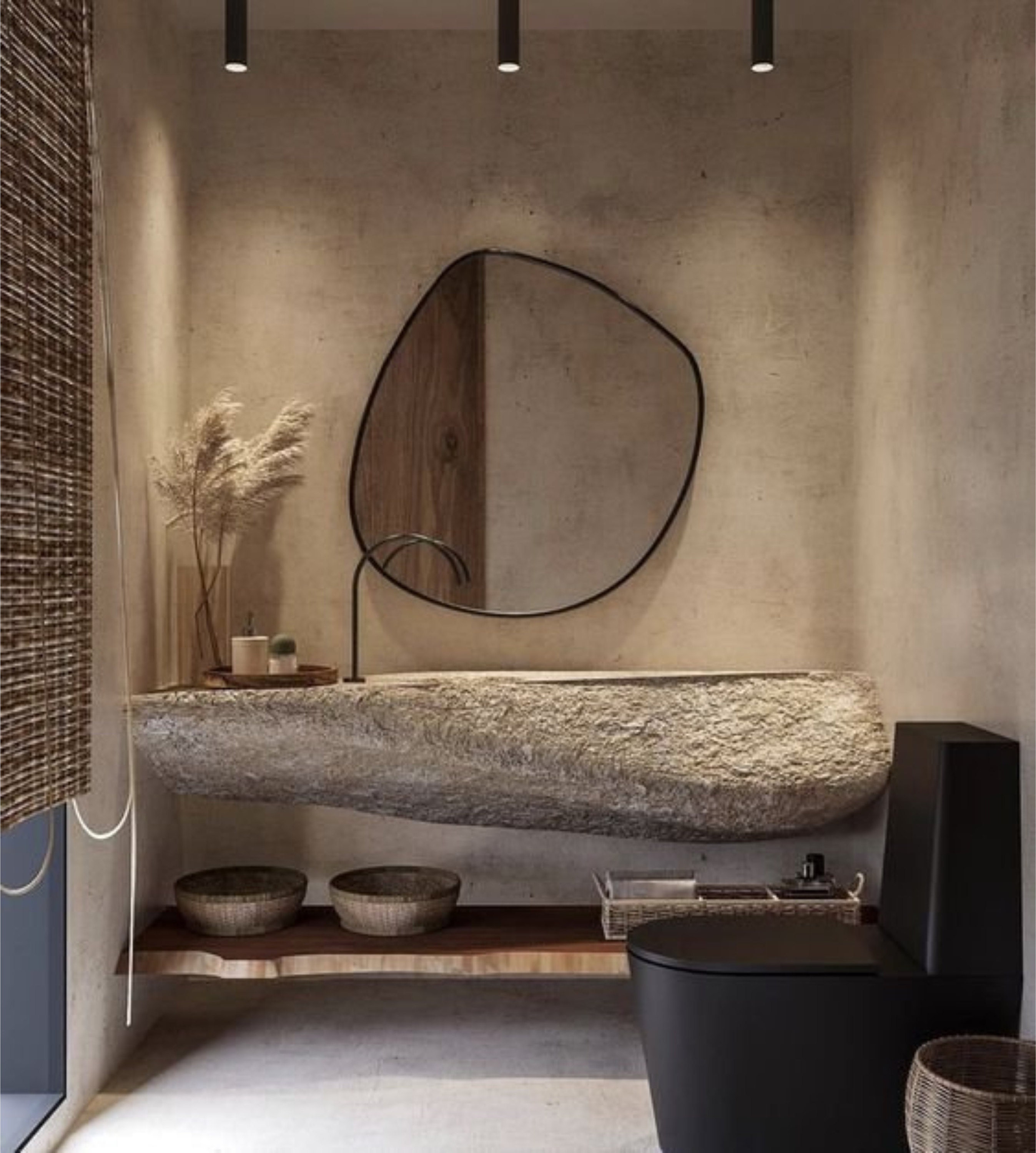 Blob mirror with black frame hung over the wall of an antique bathroom over the water basin.