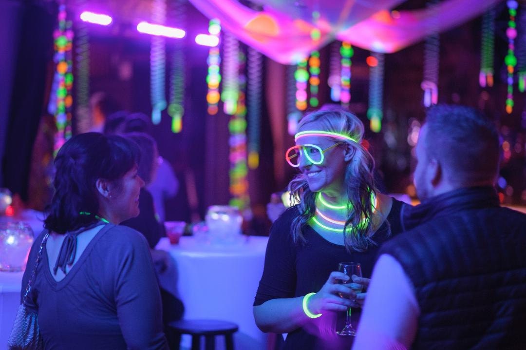 people with glow bracelets, necklaces, and glasses at black light glow party