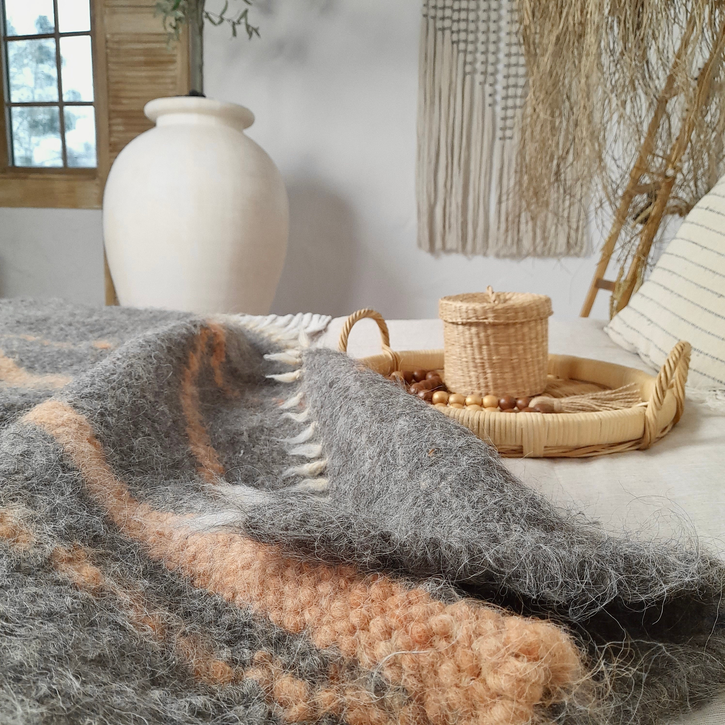 Boho style bedroom, wicker basket on the bed, wool throw blanket and wooden garland