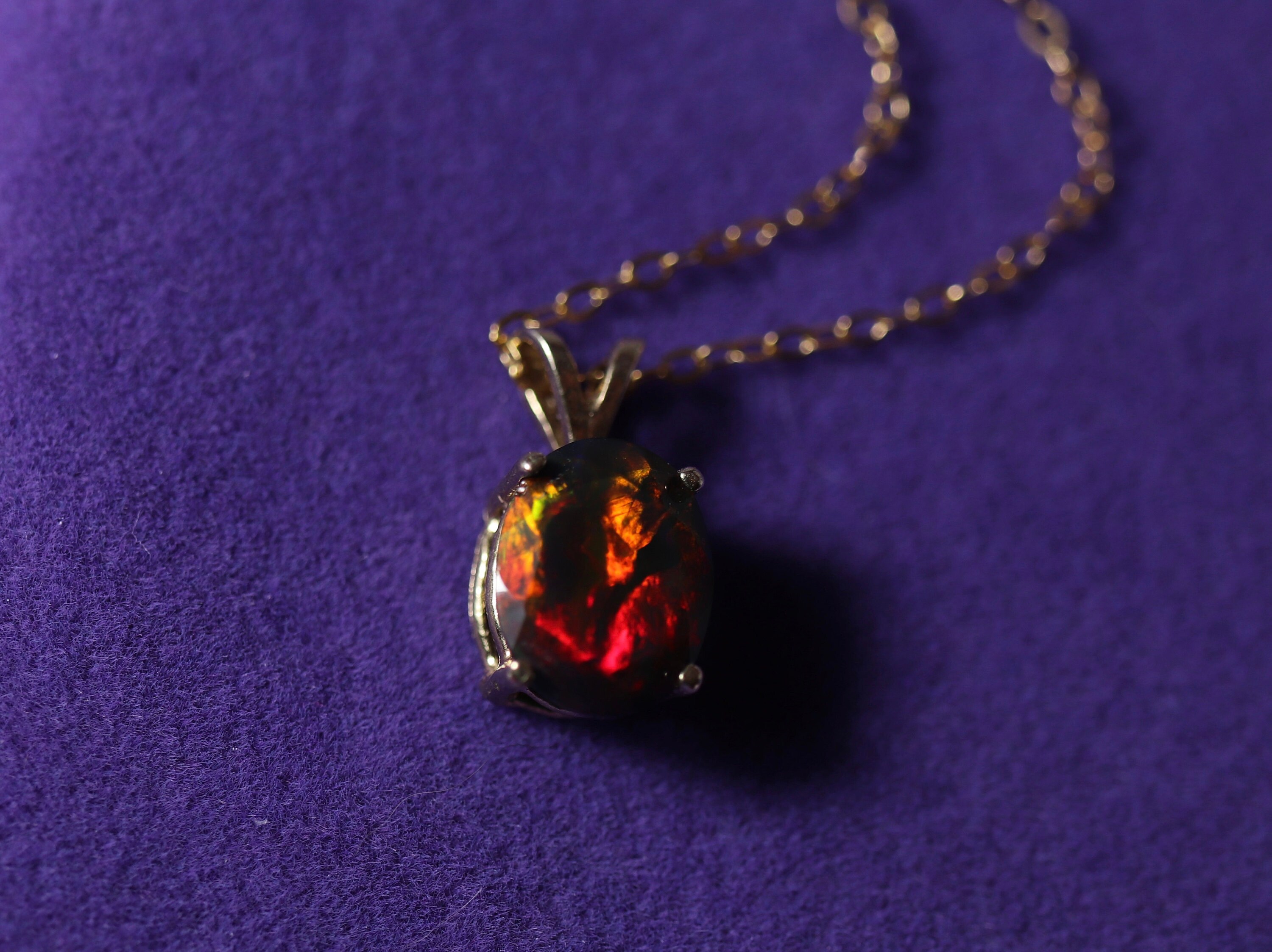 This opal has a lot of red fire in it and is considered “rare” due to its large size, perfect cut, intense colors that are very hard to find in a black opal. This photo is taken under direct light, so the opal’s fire looks it’s best and the colors are more visible. Should I take a photo of this opal under unflattering light - it would look very dark and utterly unimpressive. The same will happen with any opal: you will see it’s colors at its best under strong artificial light and later during movement while wearing the piece. It will reflect the light and flash colors at you, so it’s the most fascinating to watch. But if you take this stone in a dim lighted room and you will be utterly disappointed with it.