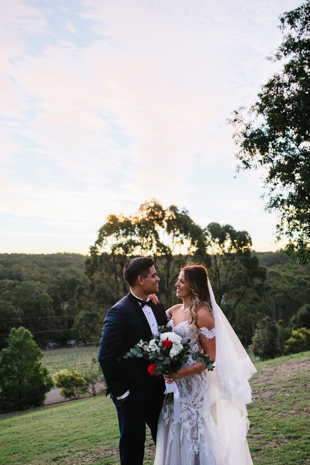 Photo of bride and groom against a sunset sky and green pastures