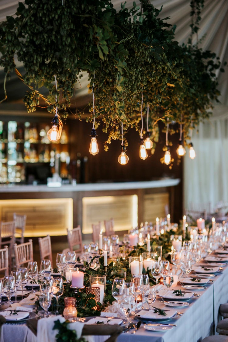 Table setting of the wedding reception with candles and blush gold stationery