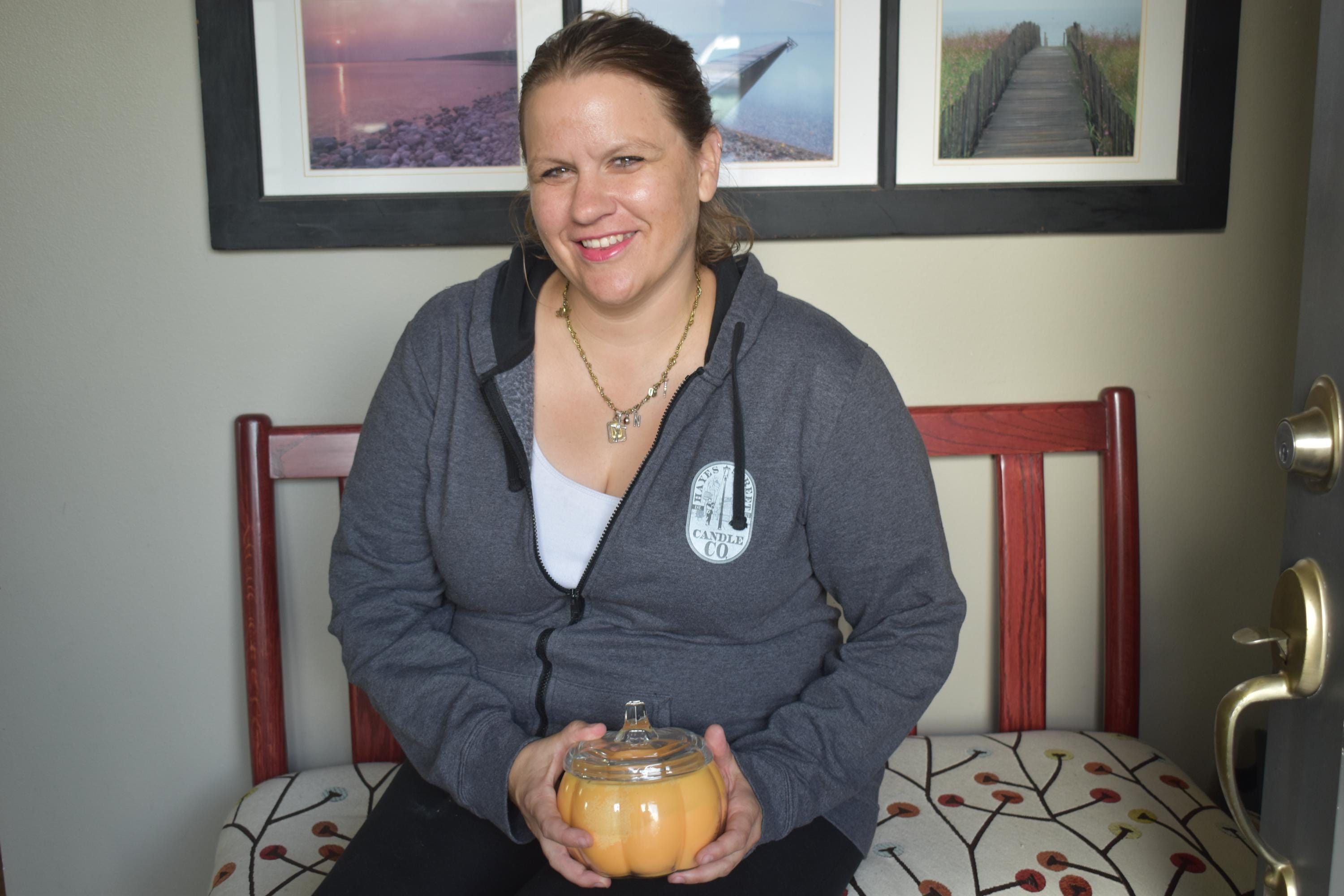 Margie Creen is photographed in her home by Racquel Muncy of the Lynden Tribune. Margie is holding an orange candle, one of her Hayes Street Candle Company products.