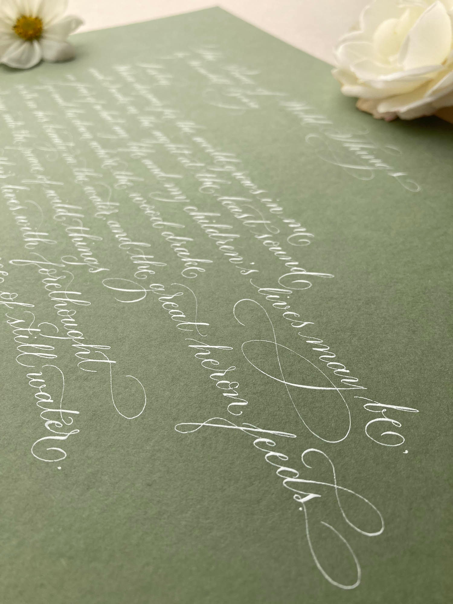 White calligraphy on sage green paper in a delicate, flourished style