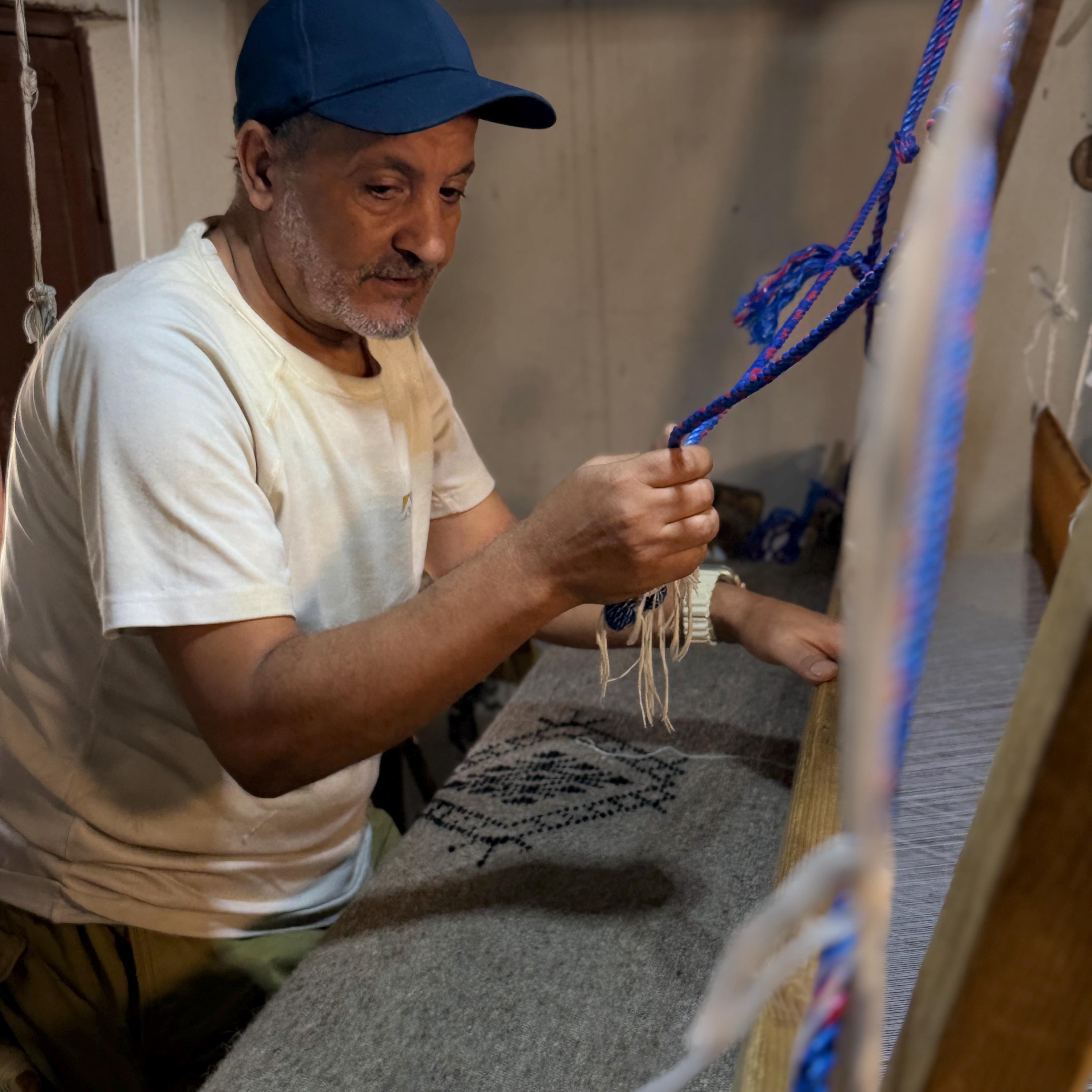 Figure 2. My father at the loom, threading the warp. A traditional Berber loom, worked by hand, one blanket at a time.