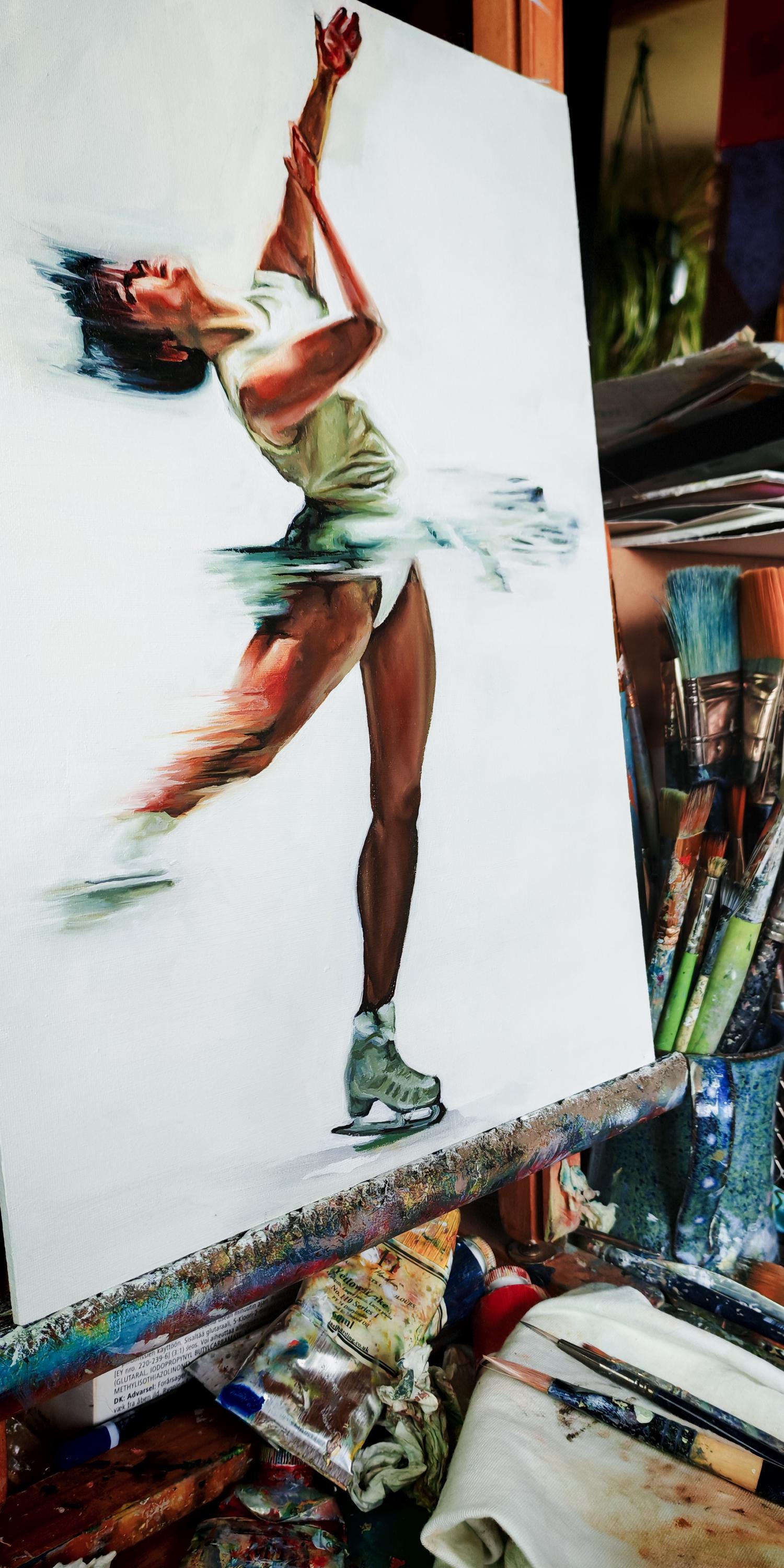 An oil painting of a figure skater spinning in a white dress on a white background sits on an easel in a messy painters studio.