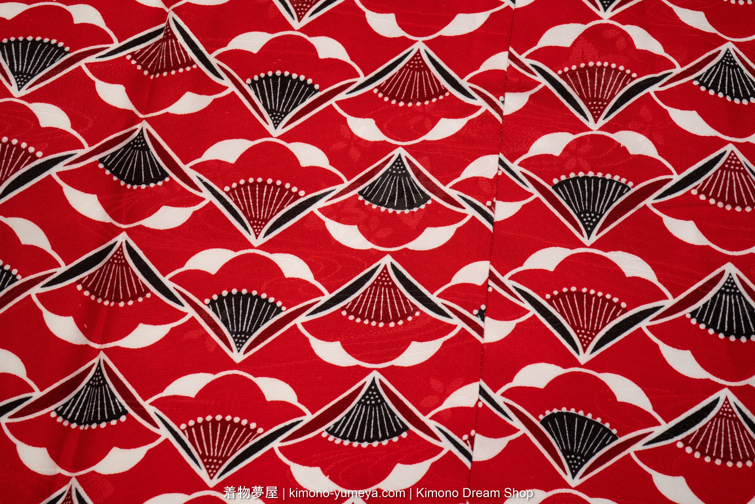 Red and black plum blossoms in the shape of folding fans creating an endlessly repeating pattern.