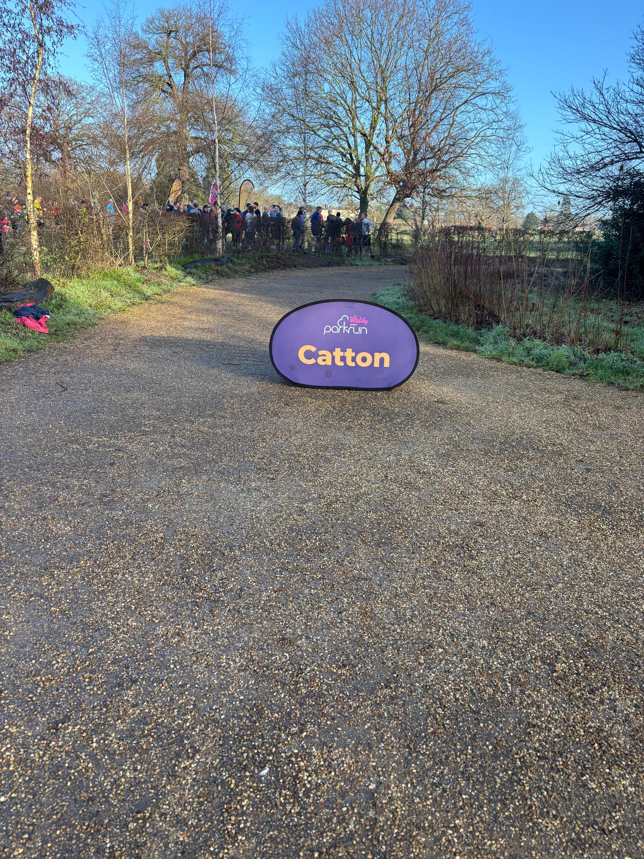 Image shows the Catton parkrun sign on a gravel track