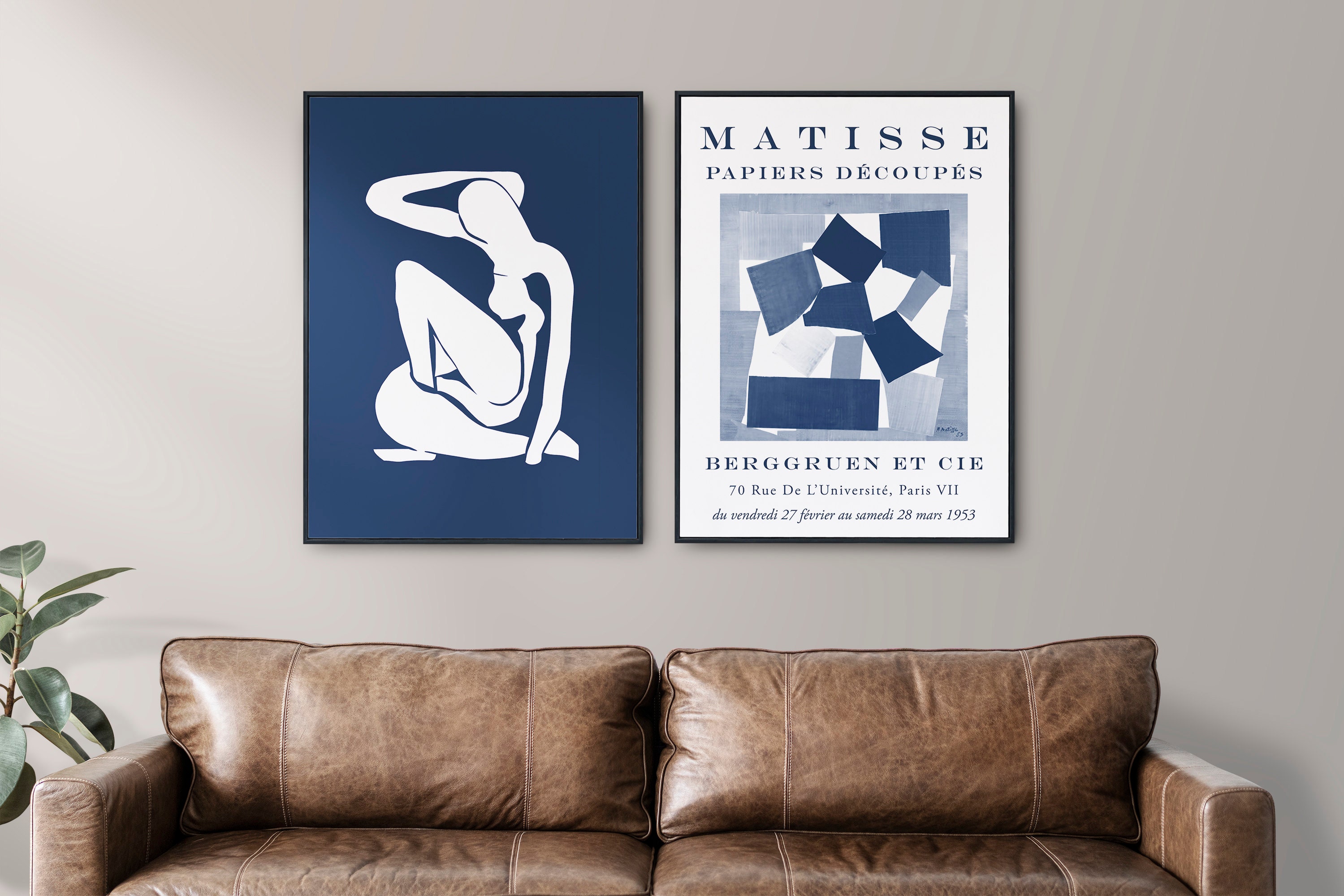 Two large art prints above a brown leather couch