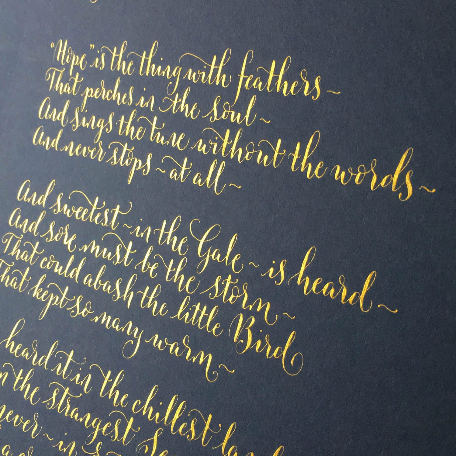 Gold calligraphy lettering in a straight up, curvy style for poems