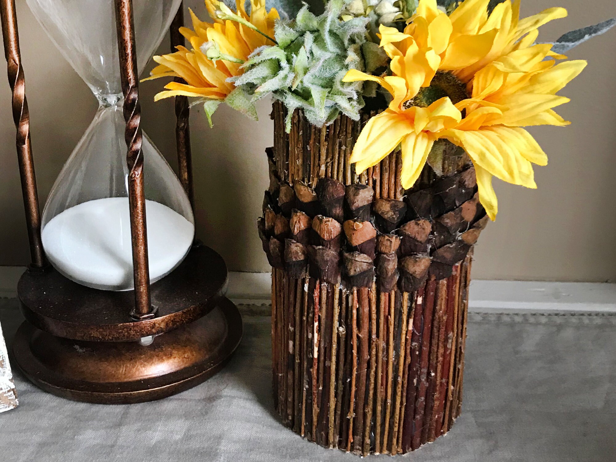 Handmade stick vase with a artificial flower arrangement.