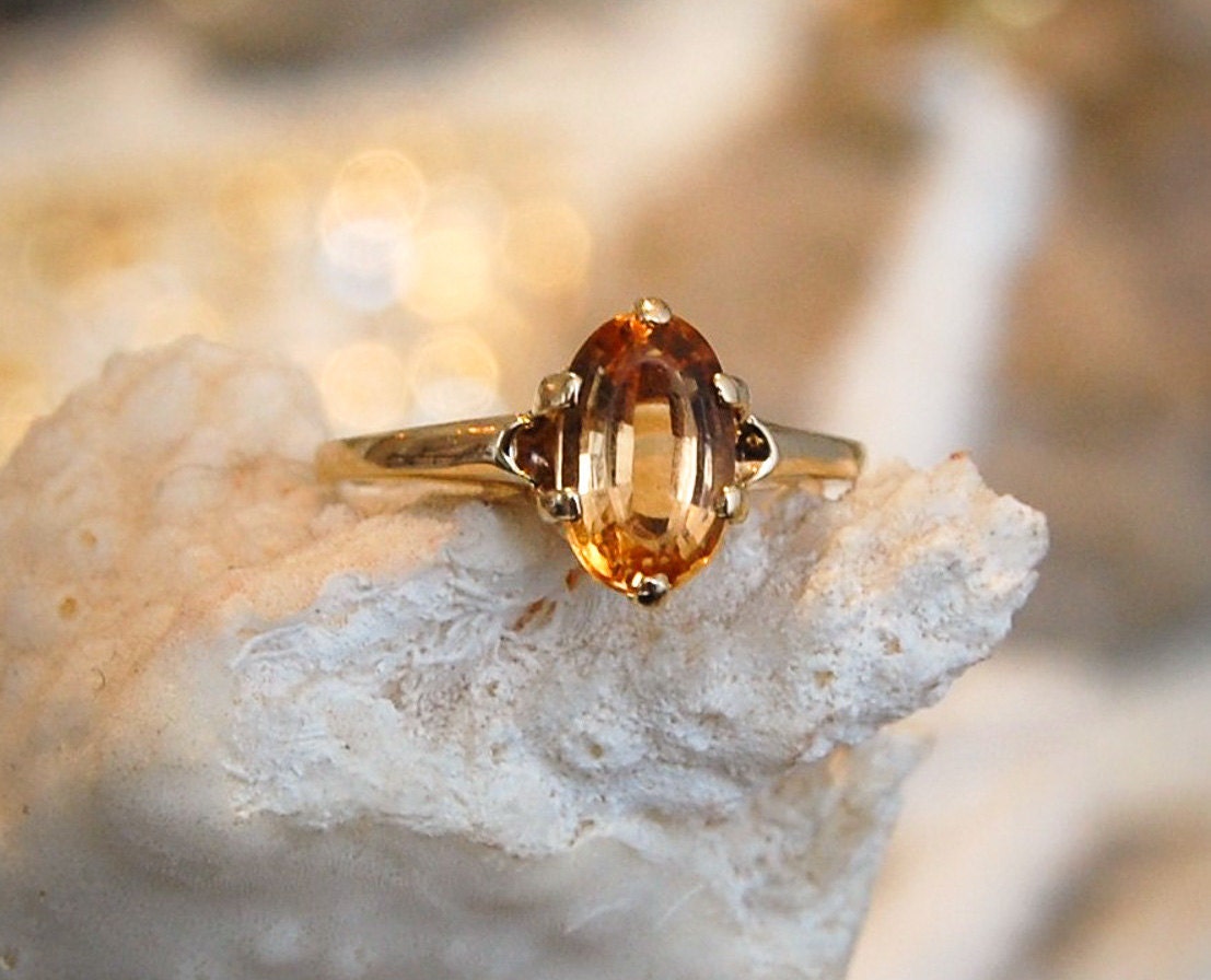 Citrine-Topaz-Gold-Solitaire-Ring-with-Amber-Golden-Hues-displayed-on-coral