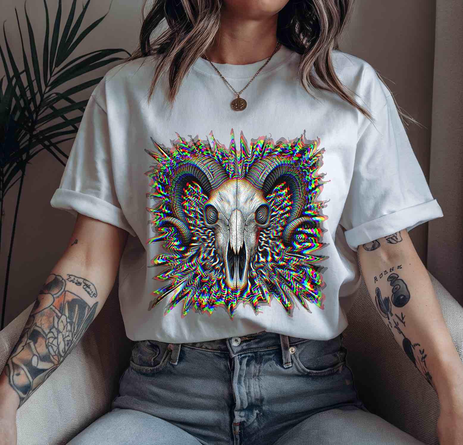 White t-shirt flat lay showing ultra-detailed ram skull linework with trippy RGB distortions, glitchcore aesthetic.
