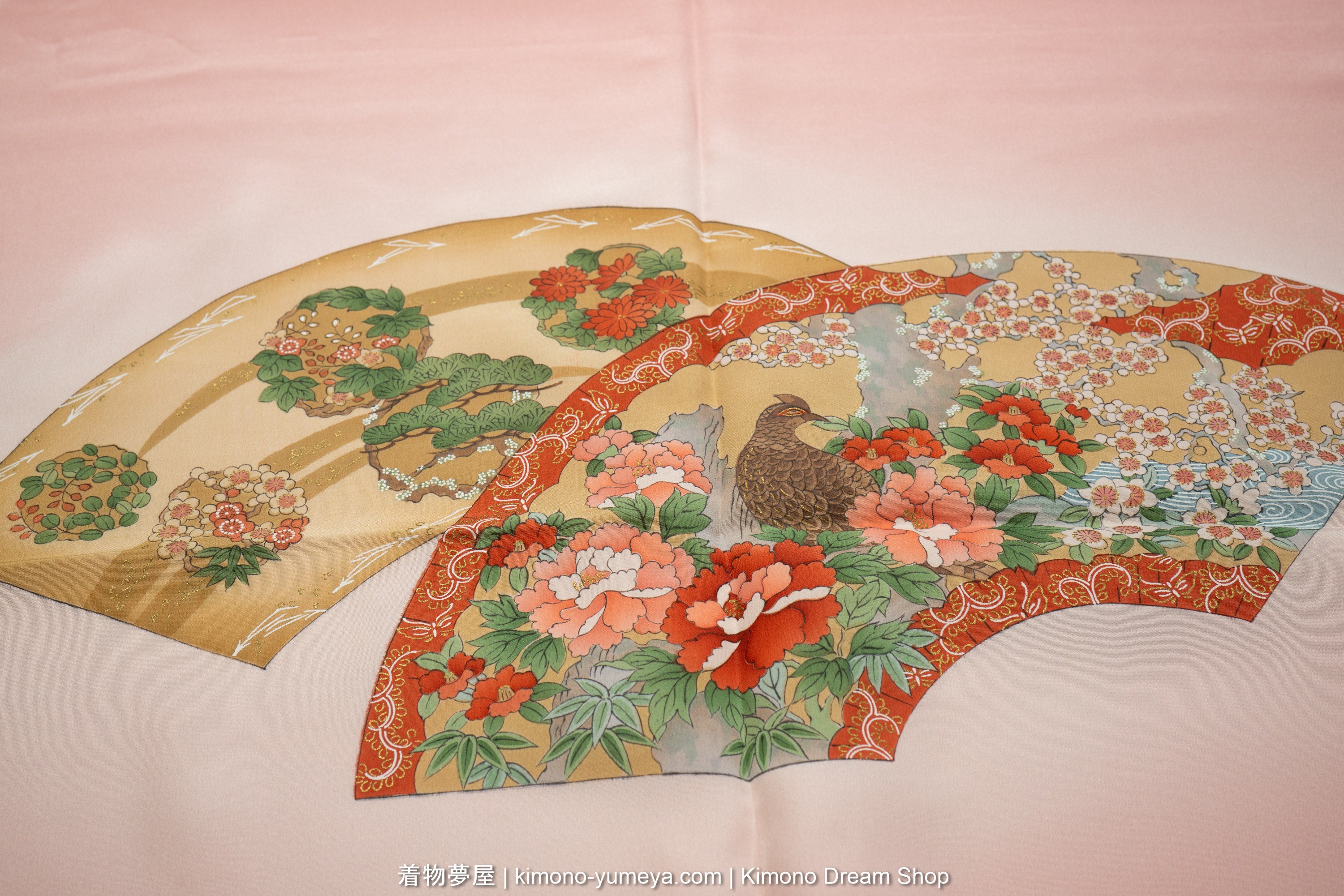Scenic springtime view of a bird amongst flowers inside a folding fan on a pink background.