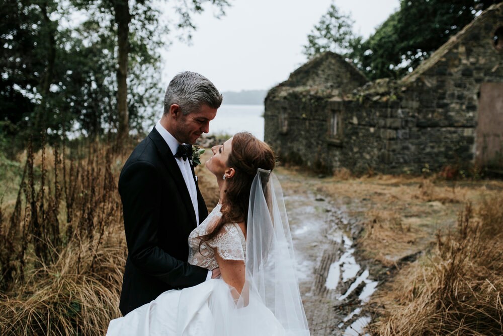 Bride and groom embracing and gazing at one another, set in the rural landscape of Ireland
