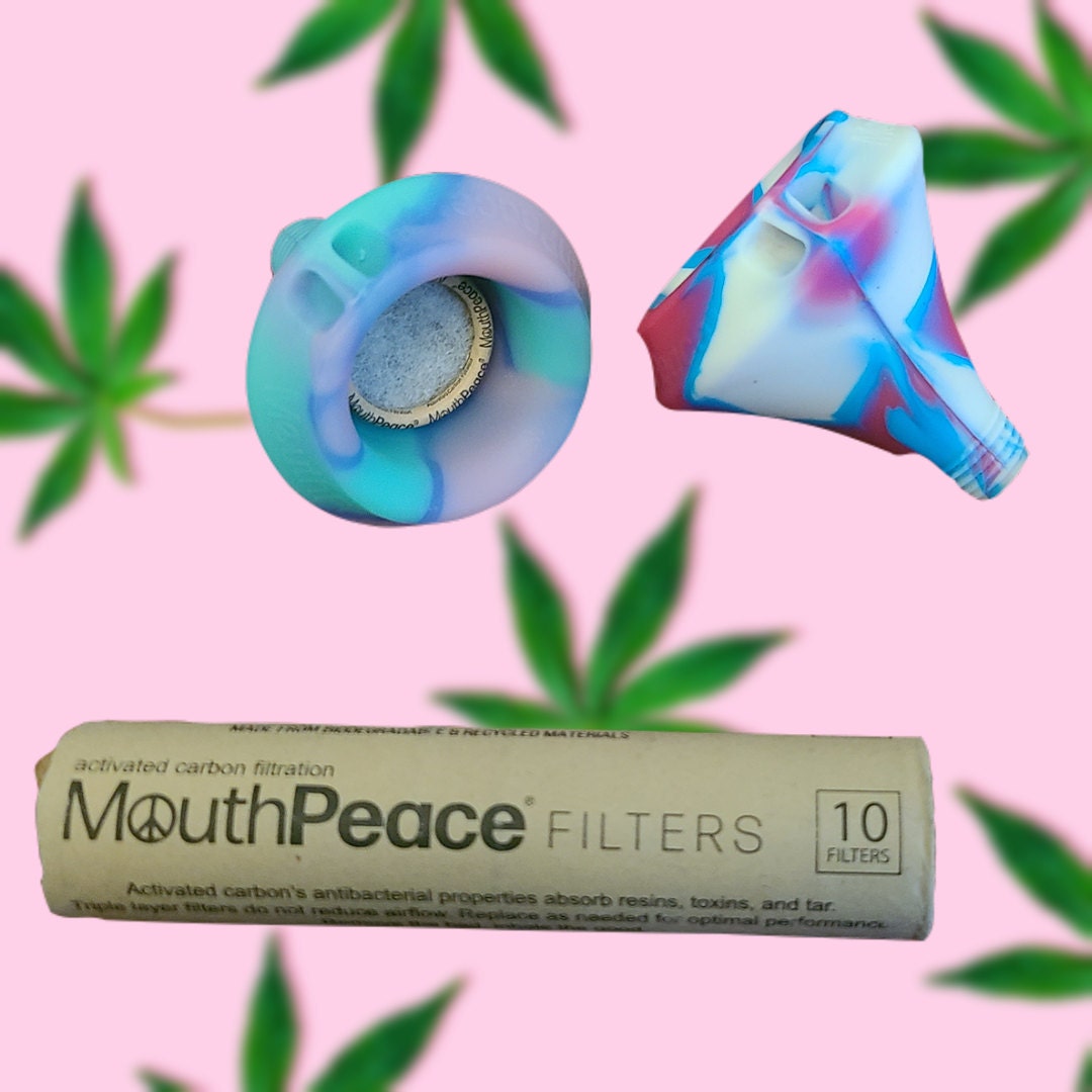 A picture of two Moose Labs MouthPeaces and a package of filters with a pink background that has blurred green leaves
