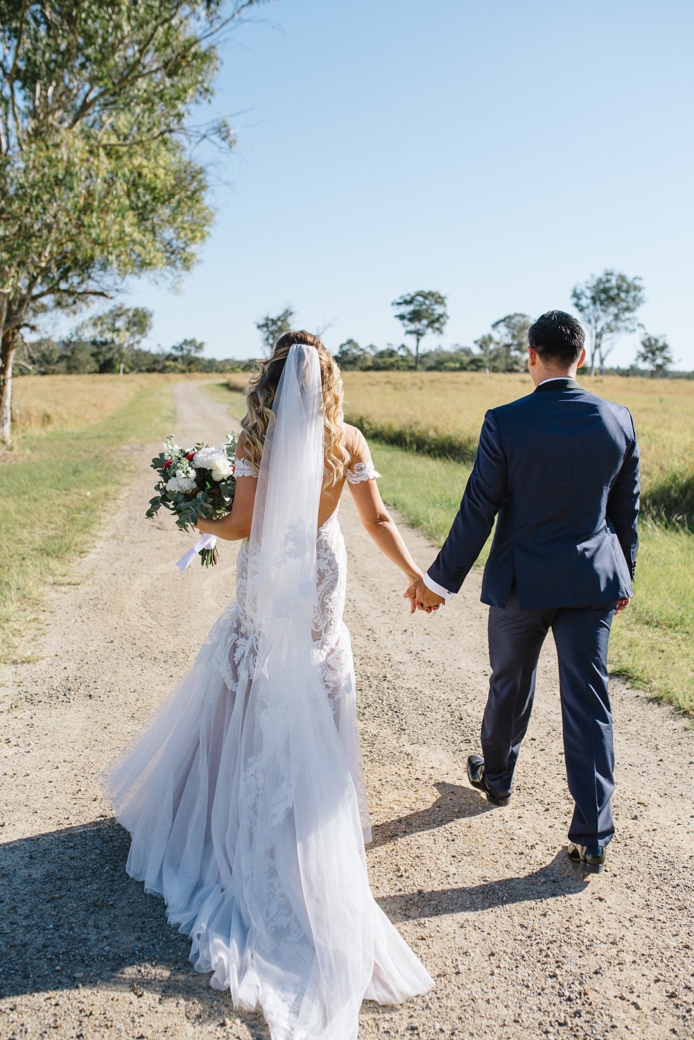 Back view of bride and groom holding hands and walking