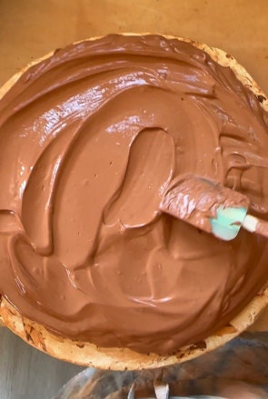 Wet red clay spread out on a circular surface to help dry it for use again. The clay looks like frosting on a cake