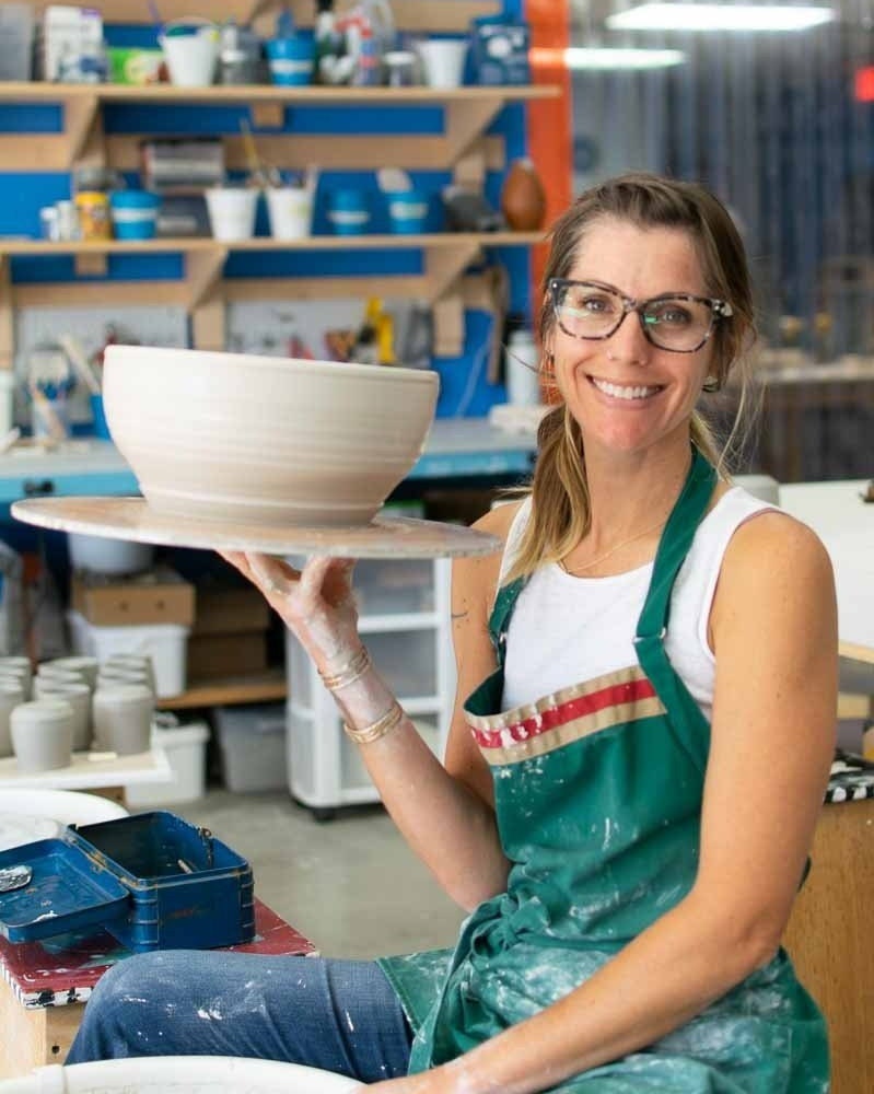 Summer by pottery wheel holding a newly thrown large salad bowl