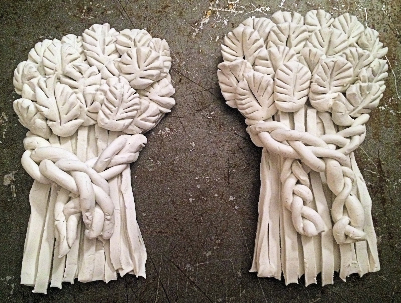 Braided clay strip placed across the wheat decoration, ready to bake