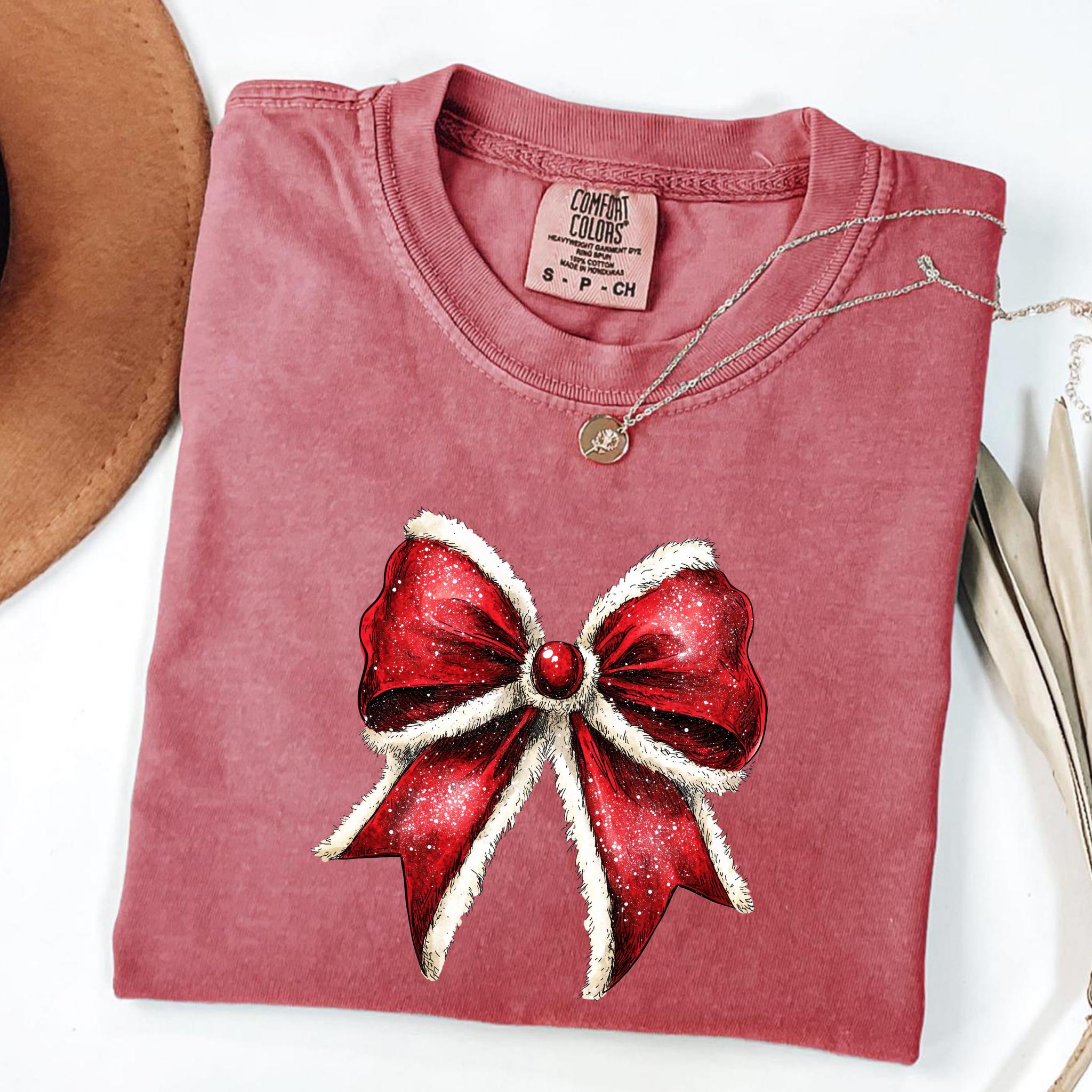Red sparkling Christmas bow design on sage green Comfort Colors T-shirt, festive holiday apparel for women.