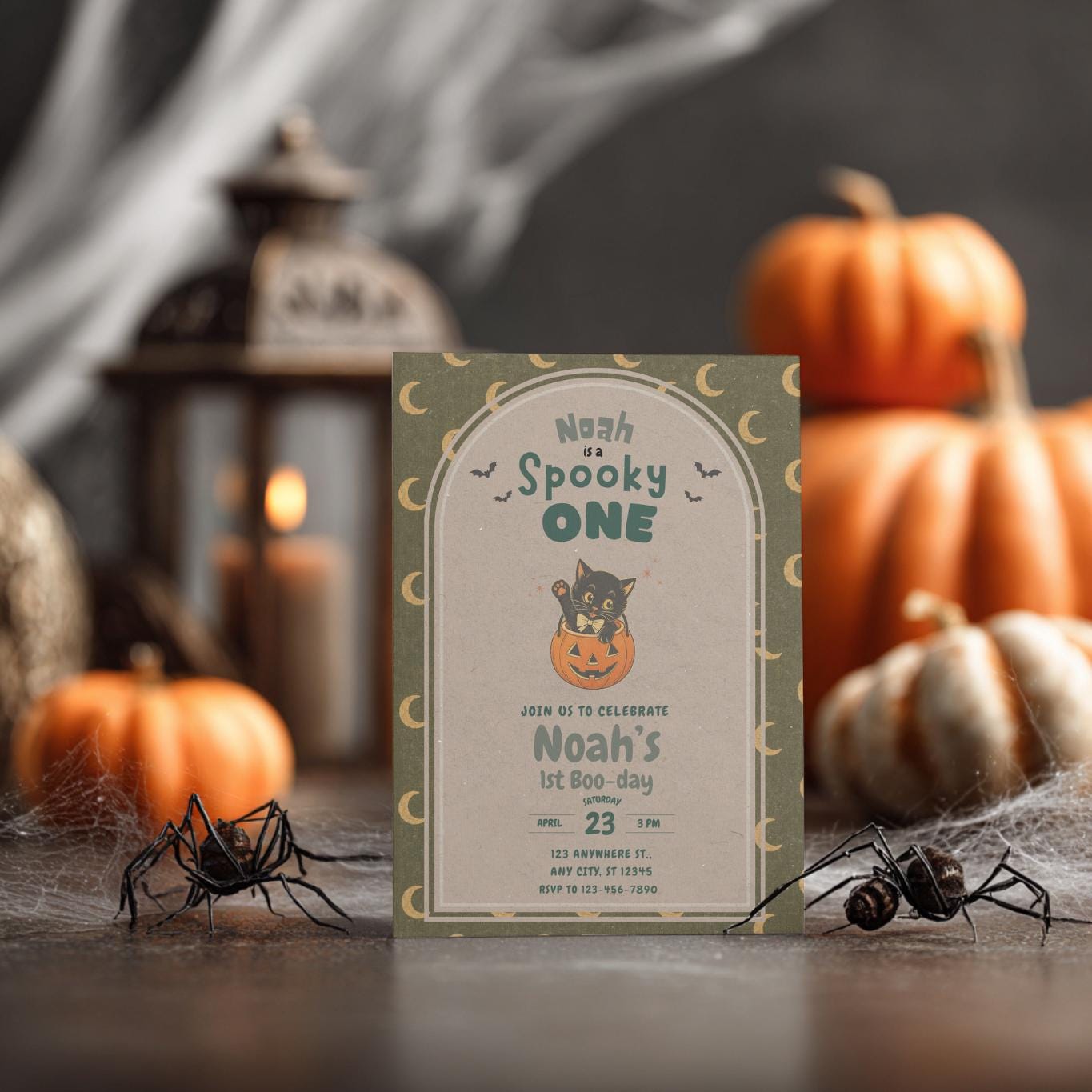 Vintage Spooky One first birthday invitation mockup with a black cat in a pumpkin, crescent moons, pumpkins, lantern, and Halloween decor.