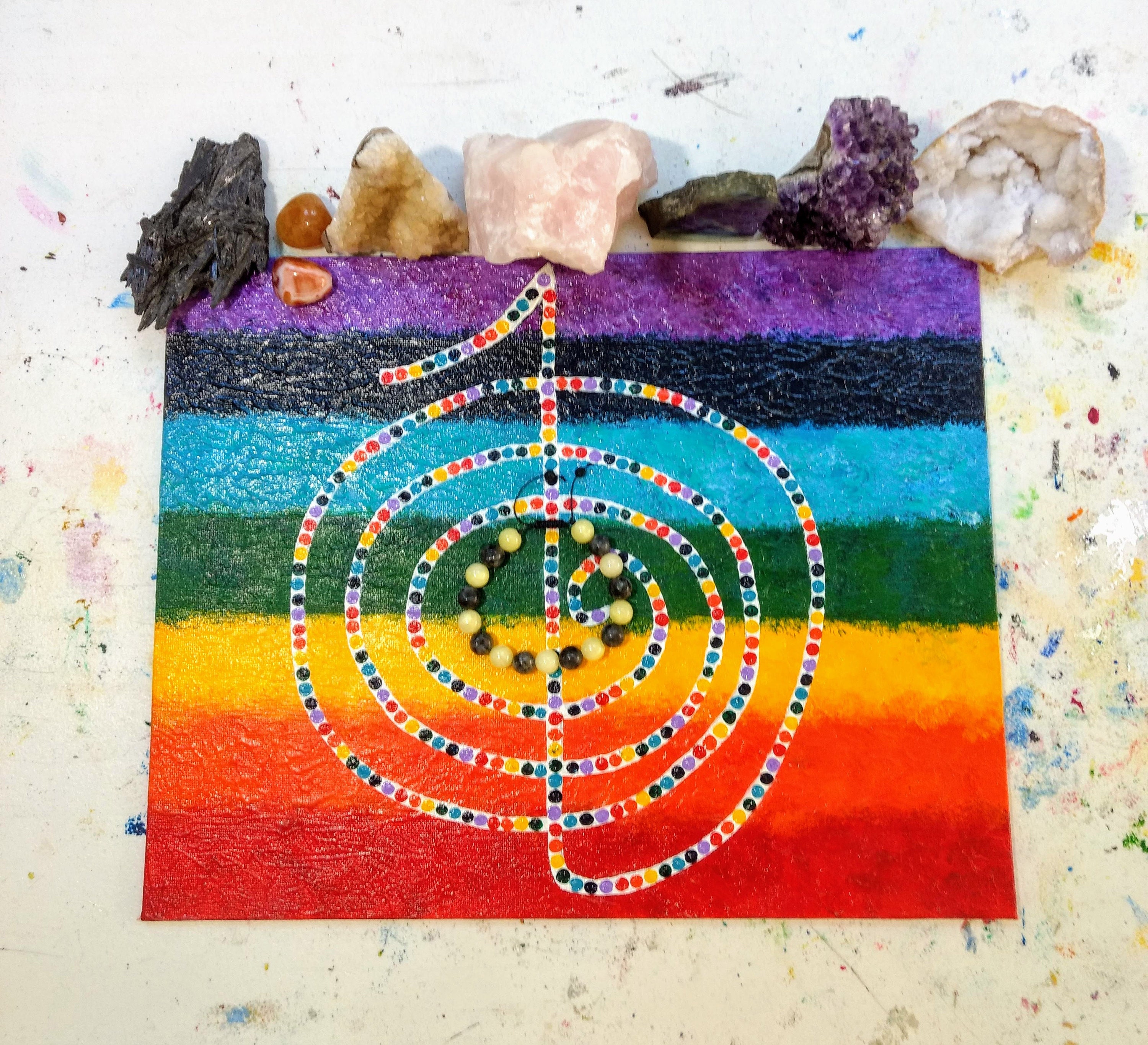 This is the Cho Ku Rei reiki symbol that I painted to put my pieces on when I reiki cleanse them. I always place the stones that I feel led to use for that particular person/sale that are good for the seven chakras at the top.