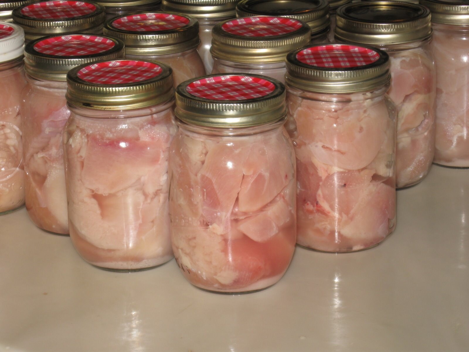 The raw chicken is placed in jars with salt and is ready to be pressure cooked