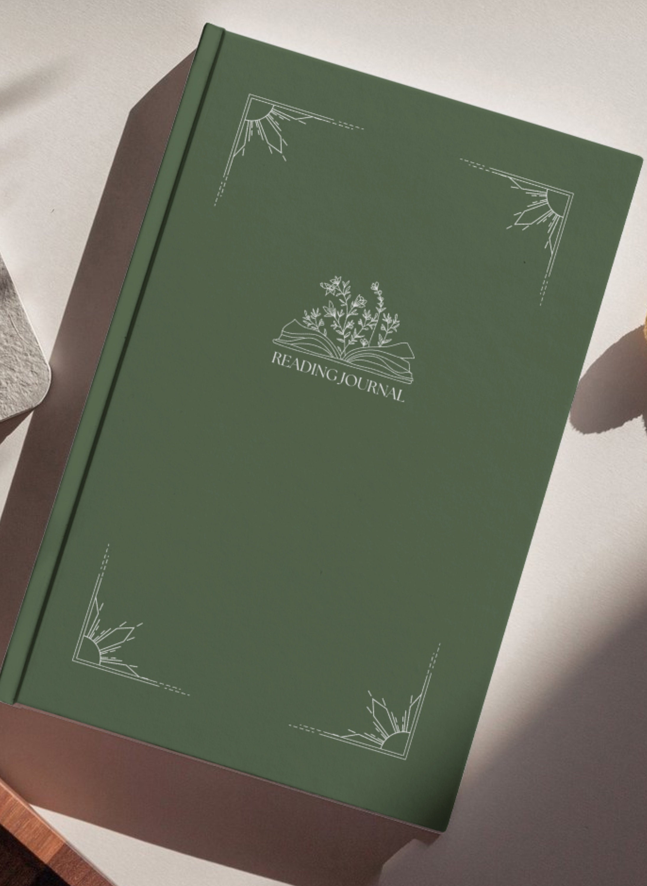dark green book, with white decorative borders and white lettering centered on the cover beneath an open book with flowers sprouted from the center, reading Reading Journal