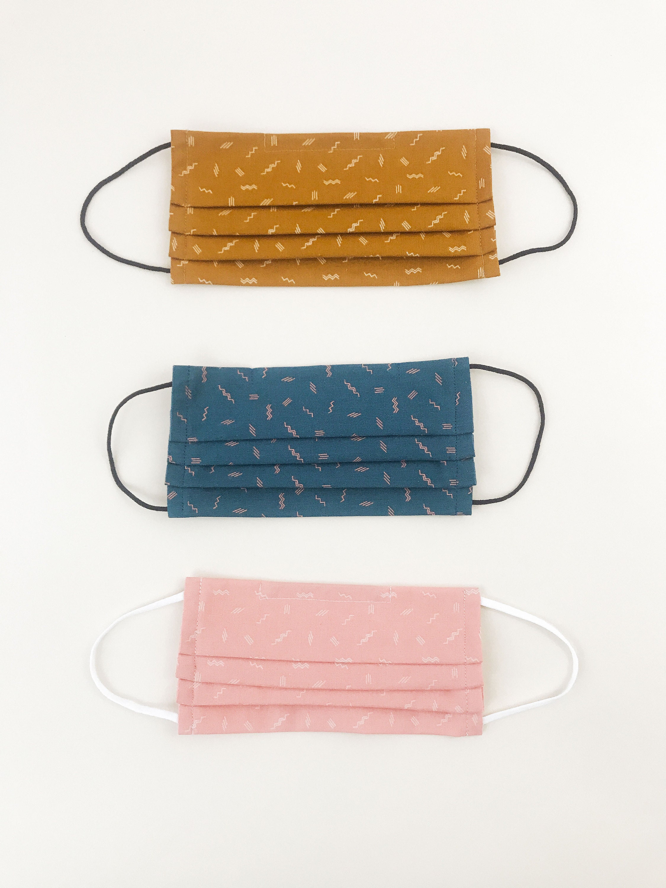 Pleated masks with elastic ear loops featuring a minimal zigzag print