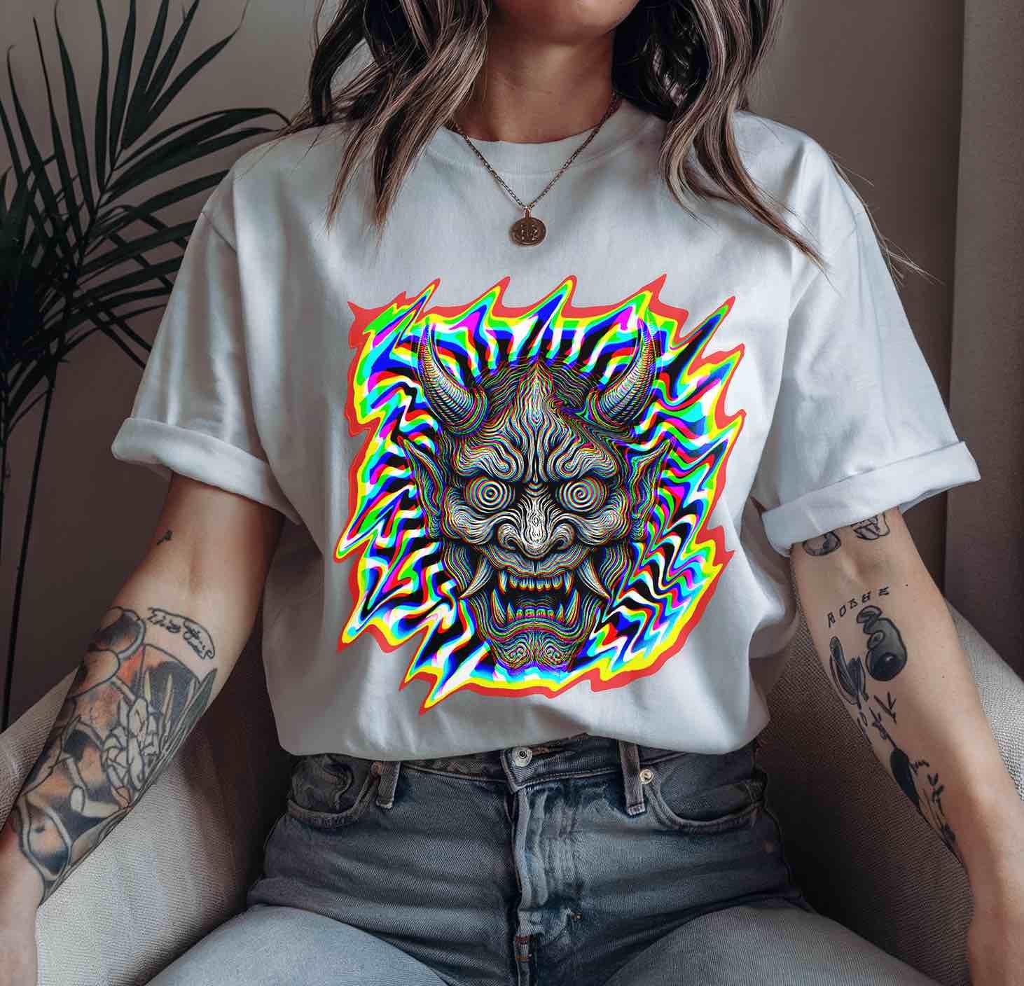 White relaxed-fit tee featuring detailed oni linework with multicolor glitch waves; alt-fashion/cyberpunk aesthetic styled with casual denim.