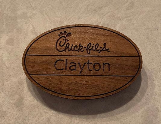 A Walnut hardwood chick-fil-a name tag with the name Clayton engraved on it.