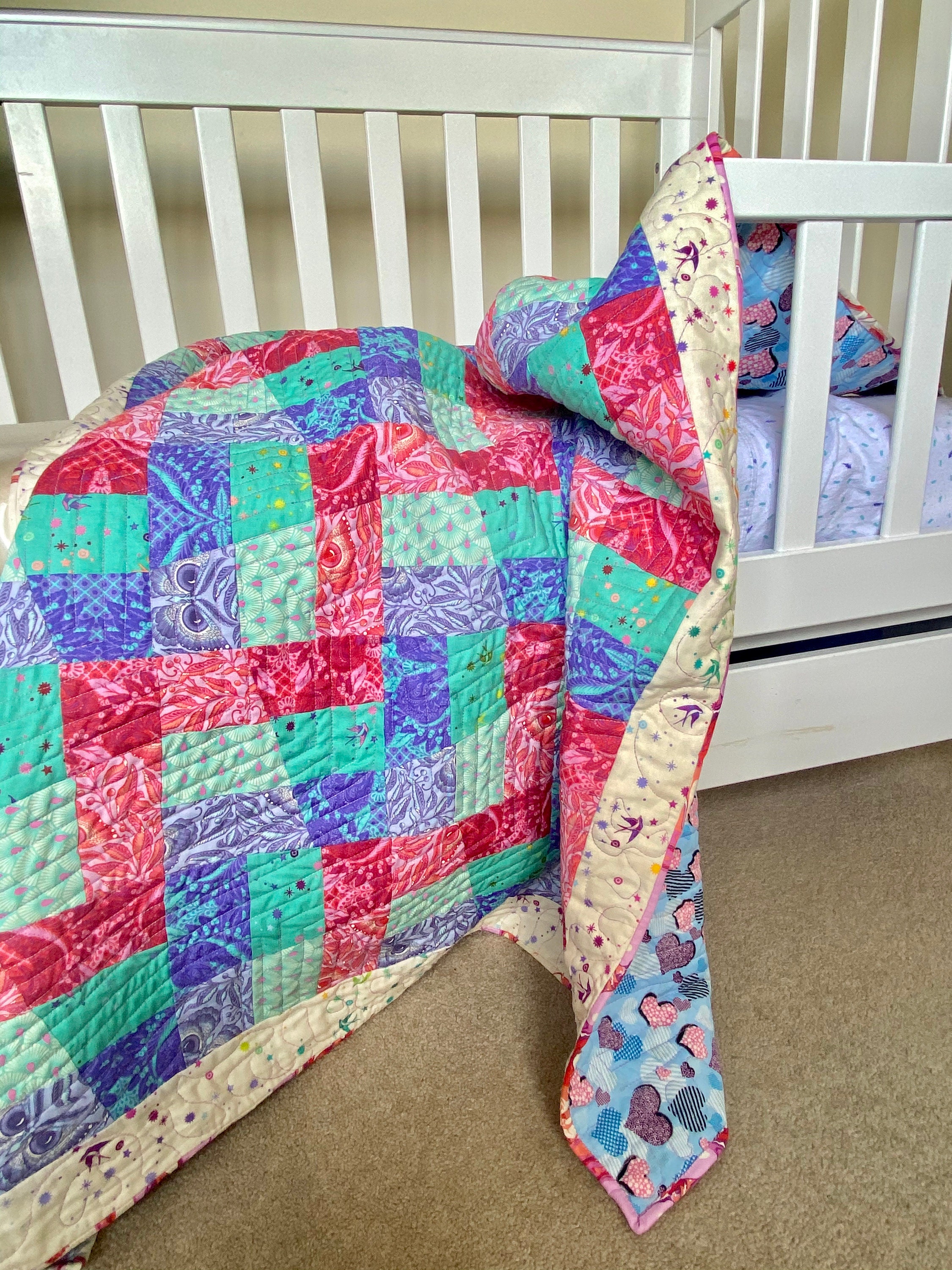 Modern Quilt Draped over the side of a toddler bed.