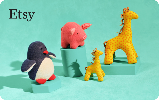 Still life photograph of plush toy animals on a teal background. On the left, a penguin with a white belly, black body and red feet. In the center, a pink pig with darker pink details sits atop a teal block. To the right, two giraffes—one large with yellow fabric and orange spots, and a smaller one with lighter yellow and orange spots—stand near each other, with the smaller giraffe in front of a shorter teal block.