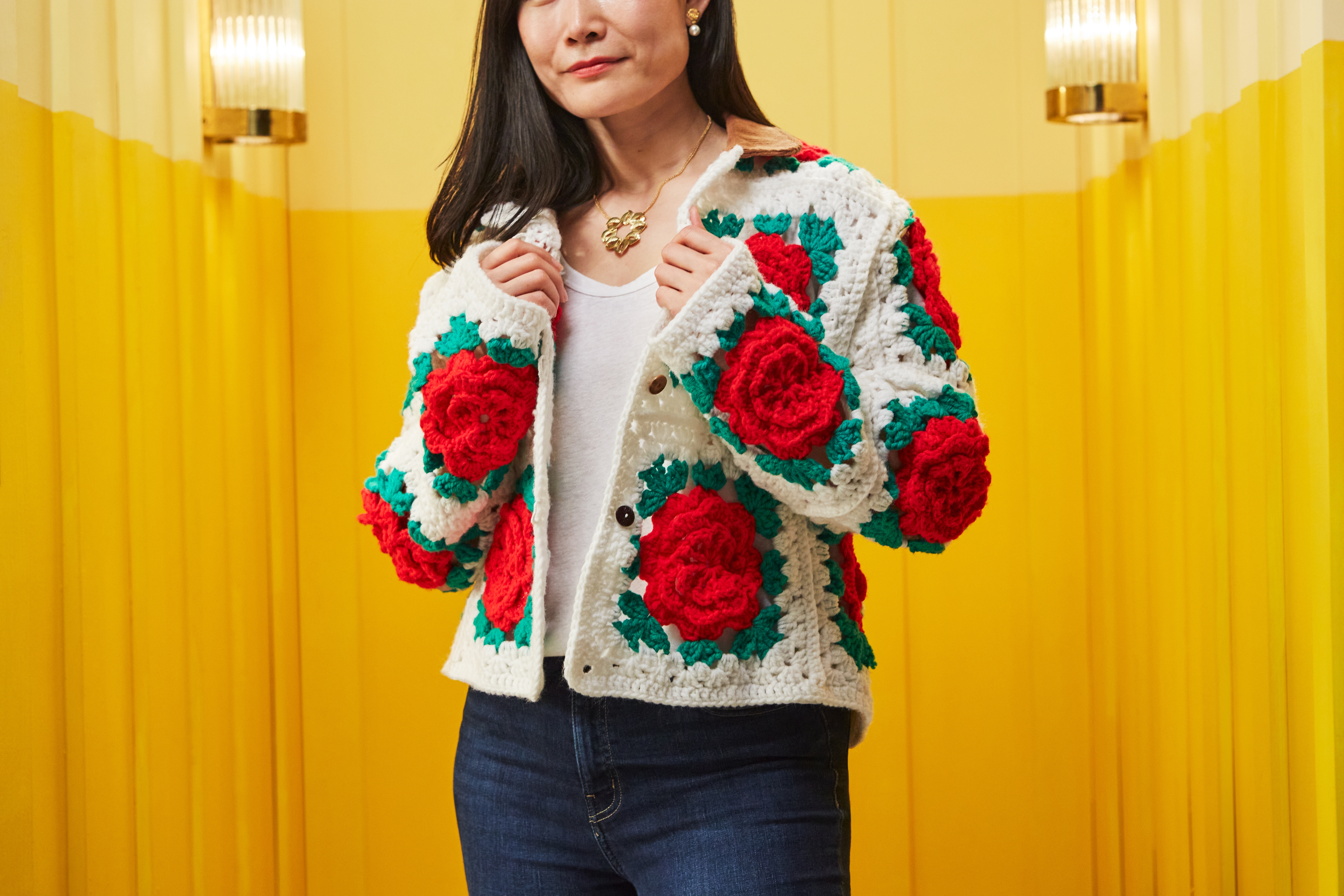 A woman wearing a crochet jumper with red roses and green leaves